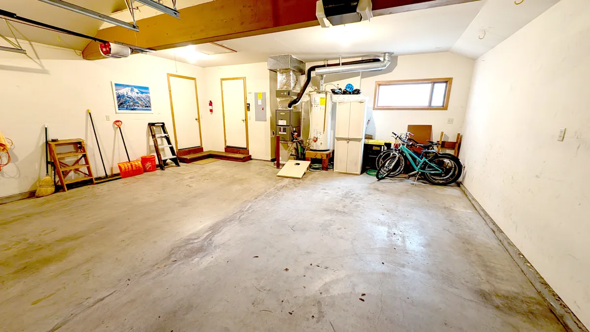 An interior view featuring bicycles stored neatly in the garage alongside other sporting gear and storage units. The space is practical and ready for family biking adventures.