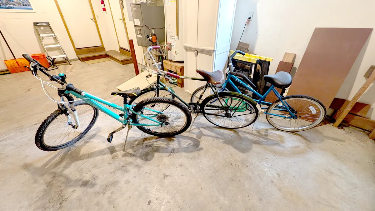 This image shows a garage space featuring three bicycles, a workbench, and tools, evoking the spirit of outdoor adventure and easy group access to Sunriver's many bike trails.