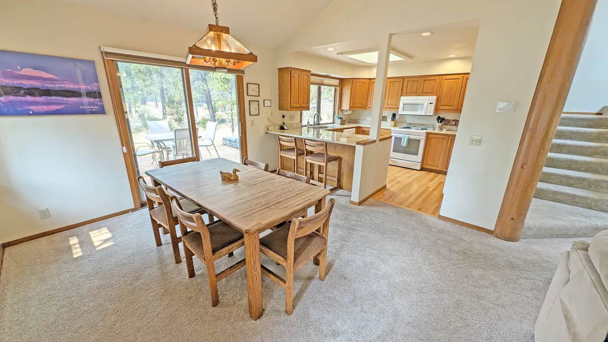A warm dining area and adjacent kitchen, bathed in natural light from large windows, creates an inviting space for preparing and enjoying meals together. The layout encourages group cooking and celebration, with views that connect the indoors to the scenery outside.